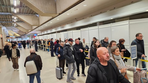 Viele Menschen warten in einer Schlange am Köln-Bonner Flughafen