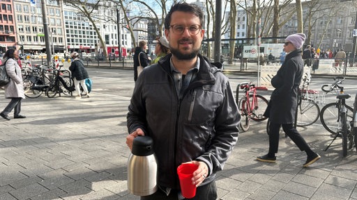 Pastoralreferent Stefan Burtscher steht mit einer Kaffeekanne auf dem Neumarkt.