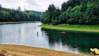 Auf einer Talsperre machen drei Frauen Standup-Paddling.
