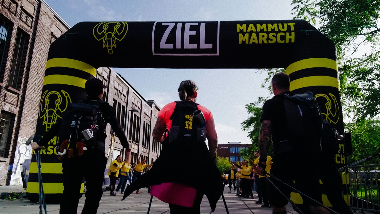 Drei Personen auf der Zielgeraden vom Mammutmarsch in Dortmund.