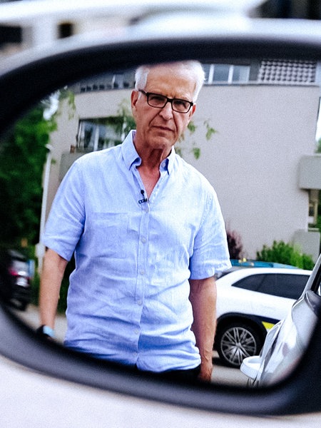 Im Seitenspiegel des Autos ist Uwe Blaschke zu sehen, der auf das Auto zuläuft.