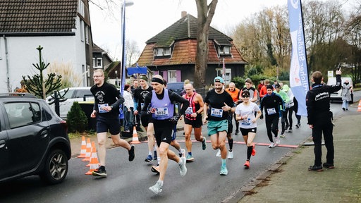 Eine Gruppe Läufer in einer Wohnsiedlung. Alle tragen Laufkleidung.