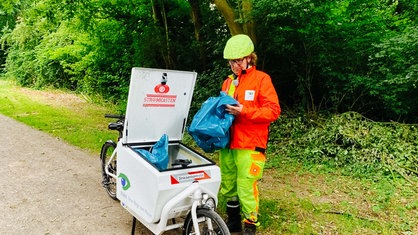 Norbert Renzke auf seinem Lastenfahrrad. Er hat einen Müllsack in der Hand. 