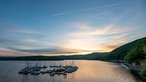 Idyllisch liegen Segelboote mitten im Rursee an einem schwimmenden Bootssteg vor Anker