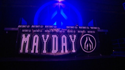 Auf einem Banner steht in pinken Großbuchstaben "Mayday"