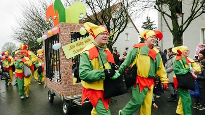 Schubkarrenumzug in Gladbeck. Zwei verkleidete Männer ziehen einen Bollerwagen.