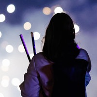 Eine Frau betrachtet vor einem dunklen Hintergrund ein Feuerwerk, sie ist nur von hinten zu sehen