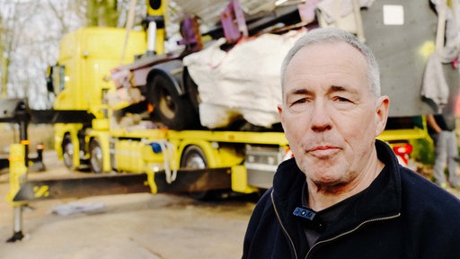 Portrait von Jürgen Liethen vor einem gelben Kranwagen.