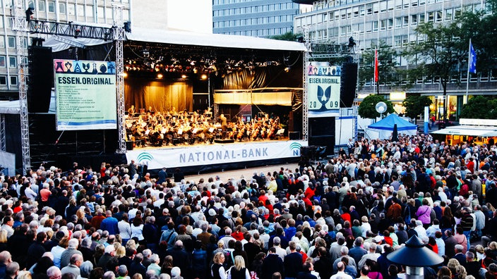 Eine Bühne auf einem Platz in der Stadt, davor viele Menschen