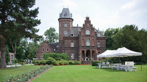 Das Backsteingebäude der Marienburg in Momheim am Rhein mit dem angrenzenden Park