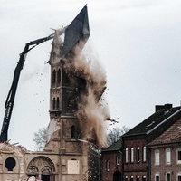 Der letzte Turm des Immerather Doms Sankt Lambertus wird abgerissen. Dabei fällt gerade die Turmspitze auf den Boden. Rechts davon leerstehende Wohnhäuser.
