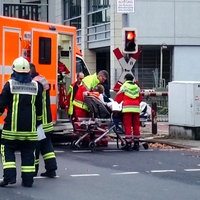 Vor einem Notarzt-Wagen versorgen zwei Rettungssanitäter eine Frau