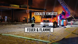 Löschfahrzeug im Wintereinsatz vor brennender Tankstelle