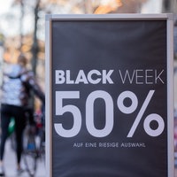 Auf einem Aufsteller vor einem Geschäft in einer Fußgängerzone steht "Black Week 50%" 
