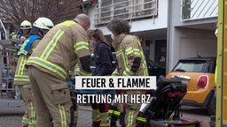 Feuerwehr-Leute tragen eine Person Richtung Krankenwagen