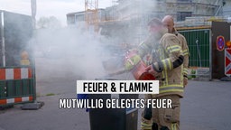 Feuerwehr-Leute löschen eine brennende Mülltonne