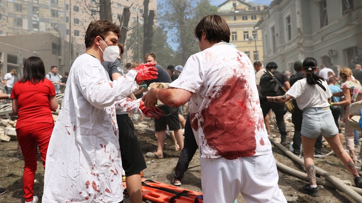 Das Beitragsbild des WDR5 Dok5 "Ohmatdyt. Ein Kinderkrankenhaus im Krieg" zeigt Rettungskräfte und medizinisches Personal die nach Opfern suchen, nachdem russische Raketen das wichtigste Kinderkrankenhaus des Landes getroffen haben. 