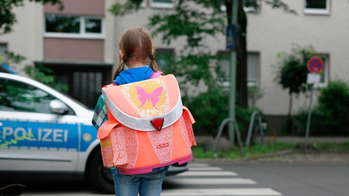 Das Beitragsbild des Dok5 "Kindesherausgabe – Wenn Eltern von Schulverweigerern das Sorgerecht verlieren" zeigt ein Mädchen mit Schulranzen vor einem Polizeiauto
