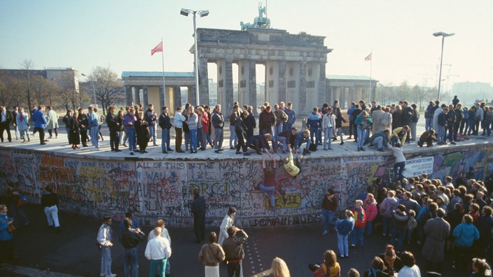 Das Beitragsbild des WDR 3 Musikporträt "Klassik als Brücke im geteilten Deutschland" zeigt Menschenmassen auf und vor der Berliner Mauer 1989.