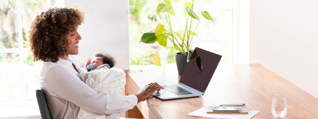 Das Beitragsbild des Dok 5 "Mütter im Job - Vereinbarkeit von Familie und Beruf" zeigt eine Mutter, die mit ihrem Säugling im Arm am Esstisch sitzt und am Laptop arbeitet. 