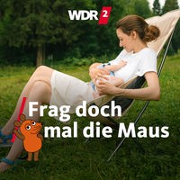 Lächelnde Frau sitzt in einem Campingstuhl auf einer Wiese und stillt ein Baby
