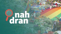 Regenbogenflaggen und Blumen am Brandenburger Tor. Links das Logo von nah dran.