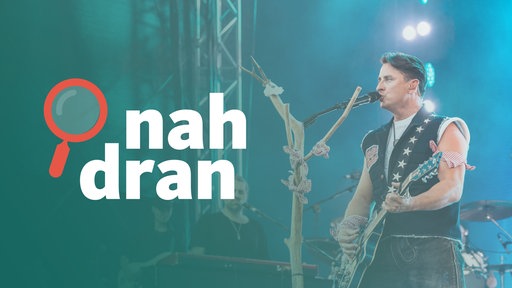 Das Bild zeigt den österreichischen Musiker Andreas Gabalier mit einer Gitarre auf der Bühne. Auf der linken Seite ist das Logo des Podcasts nah dran. 