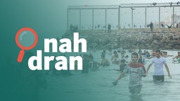 Das Bild zeigt den Strand von Ceuta, wo viele Migranten im Wasser schwimmen. 