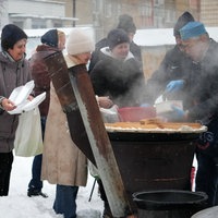 Menschen stehen bei Kälte an einer Essensausgabe unter freiem Himmel an, wo sie von Freiwilligen mit einer warmen Mahlzeit versorgt werden. (07.02.2026)