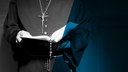 Das Beitragsbild des ARD Radiofeature "Versetzt statt verurteilt" zeigt einen Priester mit einer Kreuzkette und einer Bibel.