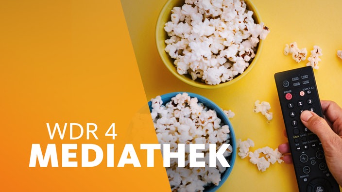 Hand an einer Fernbedienung neben zwei Schalen Popcorn