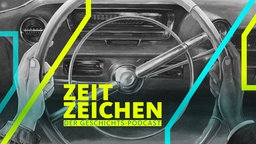 Eine weiße und eine Schwarze Hand am Lenkrad eines Autos