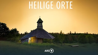 Die Quernst-Kapelle auf einer Lichtung im Nationalpark Kellerwald umgeben von Buchenwäldern im Abendlicht, vor gelbem Hintergrund; darüber der Titel der Reihe: "Heilige Orte".