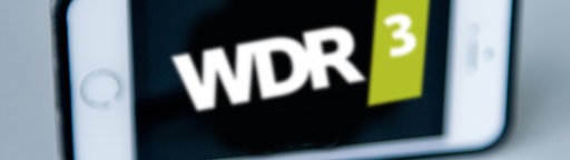 Kopfhörer liegen vor einem iPhone mit WDR 3 Sendelogo
