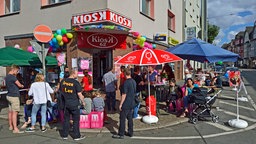 Besuchende stehen vor einem dekorierten Kiosk und feiern den Tag der Trinkhallen.