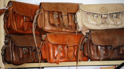 Mehrere Ledertaschen in verschiedenen Brauntönen auf einem Regal