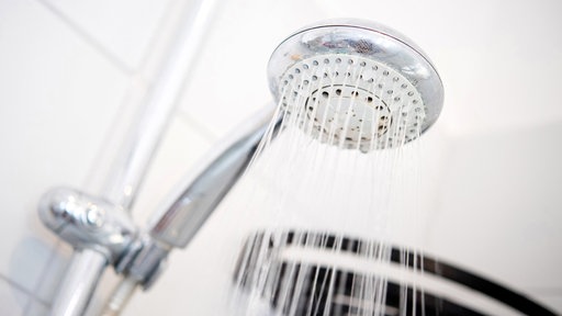 Ein Duschkopf hängt in einer Dusche in einem Badezimmer.