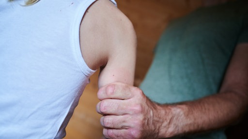 Ein Mann hält ein Kind fest am Arm (gestellte Szene).