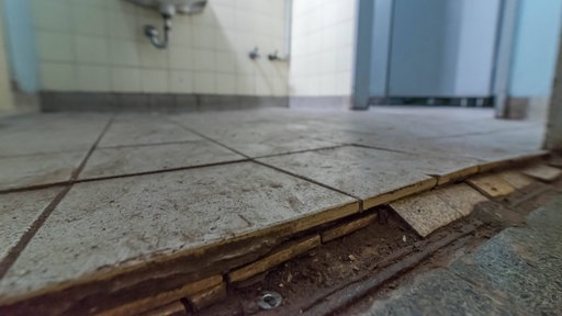 Ein maroder Boden im Toilettenraum einer Schule