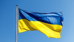 Die Flagge der Ukraine weht vor blauem Himmel