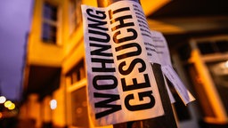 Zettel mit einem Wohnungsgesuch hängt an einer Laterne 