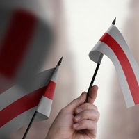 Menschen halten kleine belarussische Flaggen (rot-weiß) in der Hand