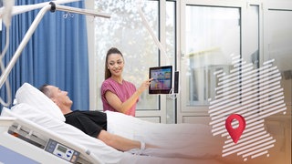 Auf der Inspire Living Lab Station steht eine Krankenpflegerin neben dem Bett eines Patienten und richtet einen Tablet-PC auf ihn aus.