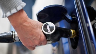 Eine Frau betankt an einer freien Tankstelle ihren Pkw. 