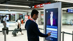 :07.08.2025, Brandenburg, Schönefeld: Die digitale Assistenz "Kiana" wird am Bahnhof Flughafen BER von Bahnmitarbeiter Ivo Kosse vorgestellt. 