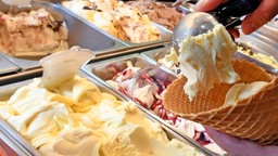 Cremiges Vanille-Eis wird in einem Eiscafe in eine Waffel gefüllt