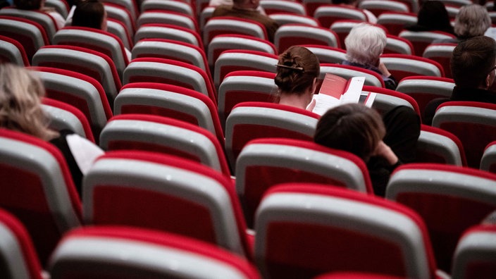  Eine Besucherin liest ein Programm im Saal des Theater Solingen.