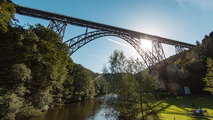 Auf der Wieser unter der hohen Müngstener Brücke befindet sich eine Wiese mit einigen Menschen darauf