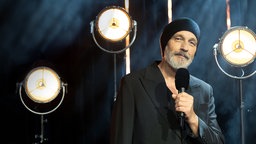 Torsten Sträter mit einem Mikrofon in der Hand.