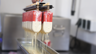 Das Bild zeigt das Milch-Sahne-Eis mit Erdbeere und weißer Schokolade in einem Behälter.